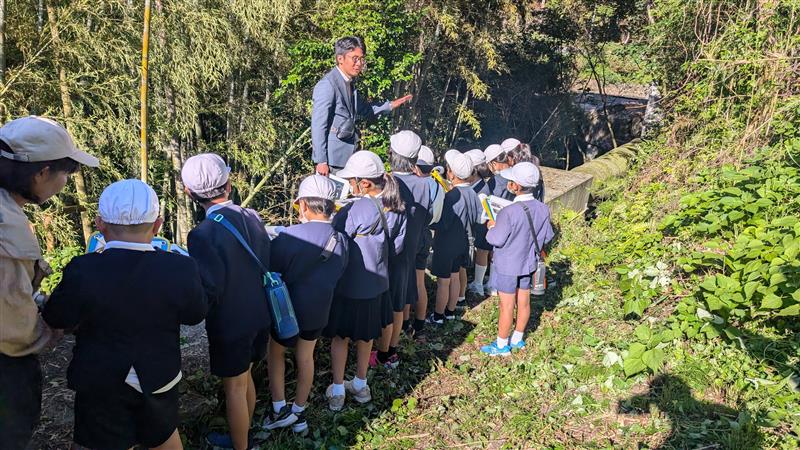 水力発電所を見学する小学生と説明する社員